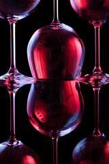 Nightclub wine glasses lit by red, blue, lilac party lights isolated on black background, object in row, nightlife concept 