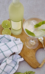 Bottle of lemonchelo seen from above next to the glass, a glass brush and the lemons. Drink with mint.