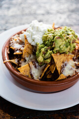 Mexican food. Nachos with guacamole, cheese and spicy sauces.