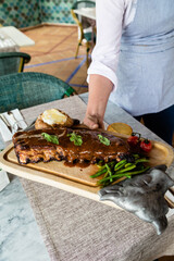 Waiter's hand serving some ribs with barbecue and cheese.