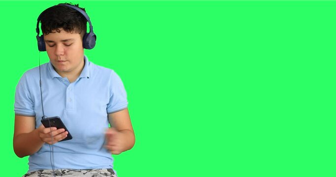 Happy teenager with headphone enjoy listen to music agains green secreen background