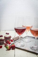 Three wines in a glass with fruit on a white table.