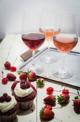 Three wines in a glass with fruit on a white table.