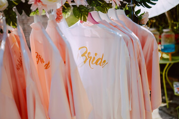 Beautiful white bathrobes for the bride and her bridesmaids hanging in the yard at a bachelorette party