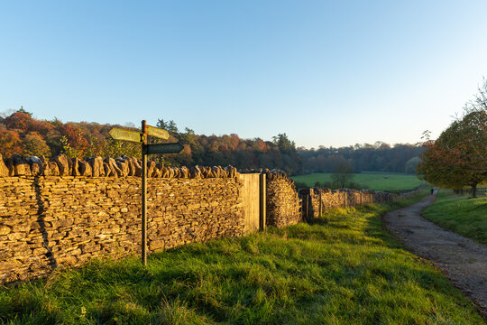 A path for a quiet autumn walk in the UK countryside with the evening sun on a stone wall