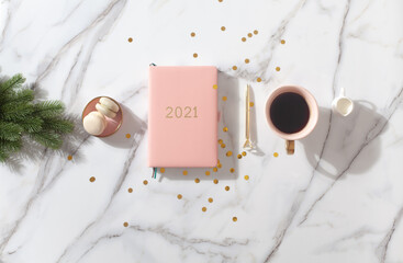 Flat lay composition with New Year's decoration, coral colored 2021 diary book and coffee cup and Macaron cookie