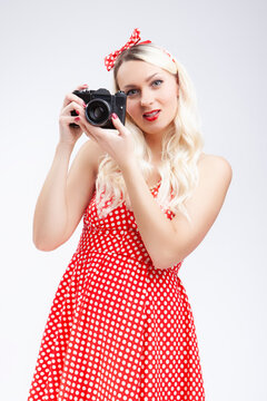Pin-up Style Ideas. Portrait of Caucasian Blond Girl Posing in Pin-up Style and Holding Retro Film Camera in Hands. Against White.