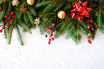 Christmas background. Twigs of Christmas tree decorated bows, balls and holly berries on white...