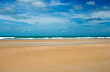 Fototapeta na wymiar Waves rolling in as the tide ebbs out on a late morning in the Indian Ocean at Cable Beach, Broome ,North Western Australia in the Summer Wet Season create a delightful tropical seascape.