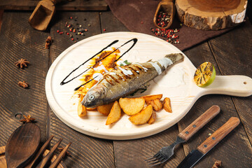 Grilled fish with potatoes on the wooden board