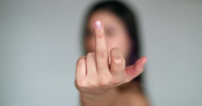 Pretty girl flipping the finger at camera, close-up young woman gives middle finger