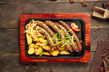 Grilled sausages with potatoes on the wooden table