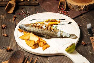Grilled fish with potatoes on the wooden board