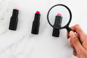 set of lipsticks with magnifying glass, analyzing make-up ingredients