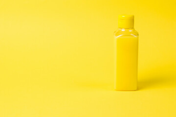 Plastic bottle with yellow liquid on a yellow background.
