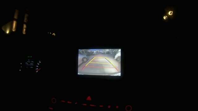 Car rearview camera view parking assistance at night, marking lines pointing right