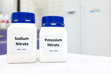 Selective focus of bottles of sodium nitrate and potassium nitrate chemical preservative. White laboratory background with copy space.	