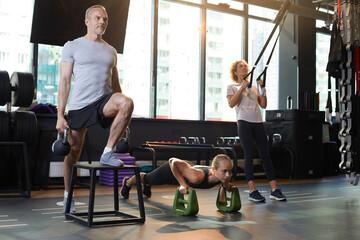 Fototapeta premium Group of people training with dumbbells and sports equipments in gym