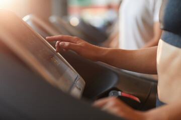 Obraz premium Close-up of young woman touching the screen o treadmill during her sports training