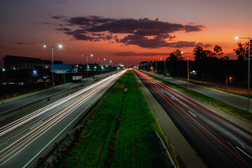 highway at night, city lights in the background, orange sky, long exposure, blurred