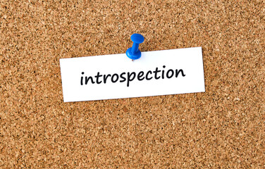 Introspection. Word written on a piece of paper, cork board background.