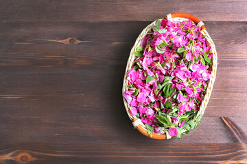 basket with rose petals and flowers for listening on a dark wooden table. space for text, flat layout.
