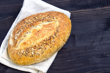 Rye bread with sunflower seeds and flax seeds on a dark wooden background. Fresh bread. Close-up. View from above. Copy space for text.