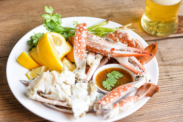 Crab meat with beer / Cooked crab claws and legs on white plate and seafood sauce on the table , blue swimming crab /