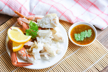 Crab meat - Cooked crab claws and legs on white plate and seafood sauce on the table , blue swimming crab