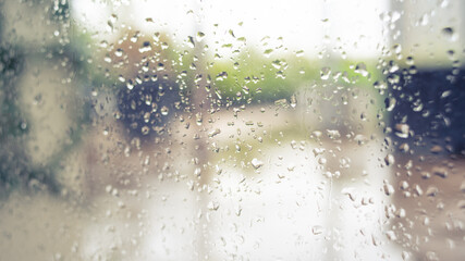 blurry garden view through window with rain drops in warm theme