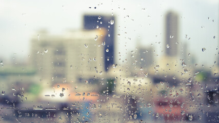 Bangkok city view through window with rain drops in warm theme