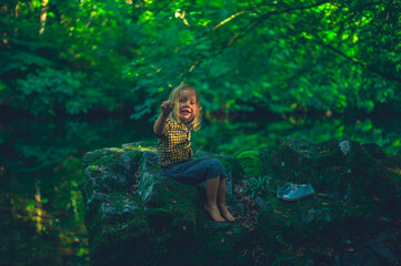 Fototapeta na wymiar Preschooler playing by brook in the woods