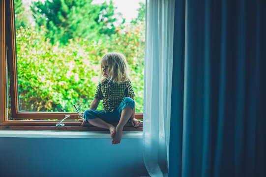 Preschooler sitting on window sill