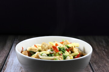 Traditional spicy fried and stirred sliced fresh baby corn, chopped dried tofu, chilly, mushroom and Chinese celery in the bowl. Famous vegetarian menu in Asia restaurant. 