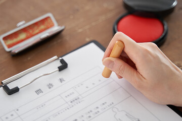 書類に個人の印鑑を押す日本人女性の手元