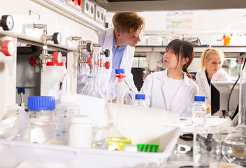 Portrait of male and female scientists in white coats working at biochemical laboratory