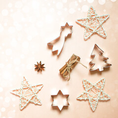 Christmas decorations: stars, toys, snowflakes. New Year's forms for cookies: Christmas tree, stars. Flat lay on light background with bokeh