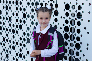 Portrait of pretty schoolgirl wearing stylish uniform with backpack holding colorful notebooks. Back to school concept