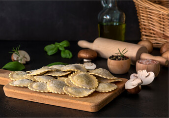 Obraz na płótnie Canvas Fresh raw italian filled pasta ravioli or tortelli with mushrooms, pesto, and ricotta.