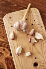 Clove of garlic with peppercorn on the wooden chopping board