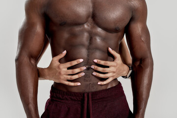 Perfect abdomen. Female hands embracing, touching muscular african american man abs isolated over...