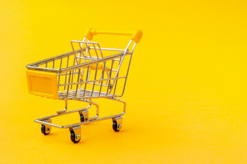 Empty shopping trolley on the yellow background