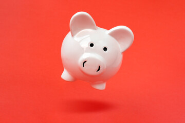 Piggy bank levitating over a red background