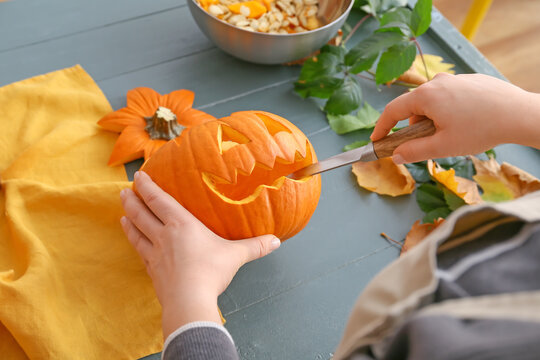 Woman carving pumpkin for Halloween at table