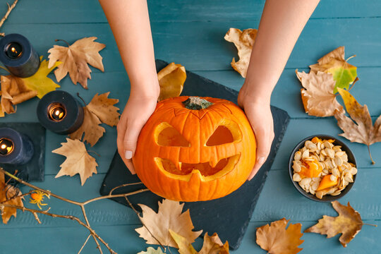 Woman with carved Halloween pumpkin at table, top view