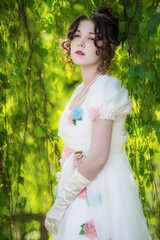 Girl in a long, elegant white bride dress in a park.