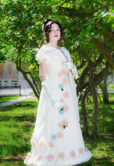 Young woman in an long white bride dress in flowers tree
