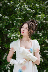 Young girl in an long white bride dress in flowers tree