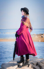Portrait girl in a crimson coat against background of sea