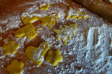 Shortbread cookies of different shapes on a wooden table with flour. Cooking, baking.